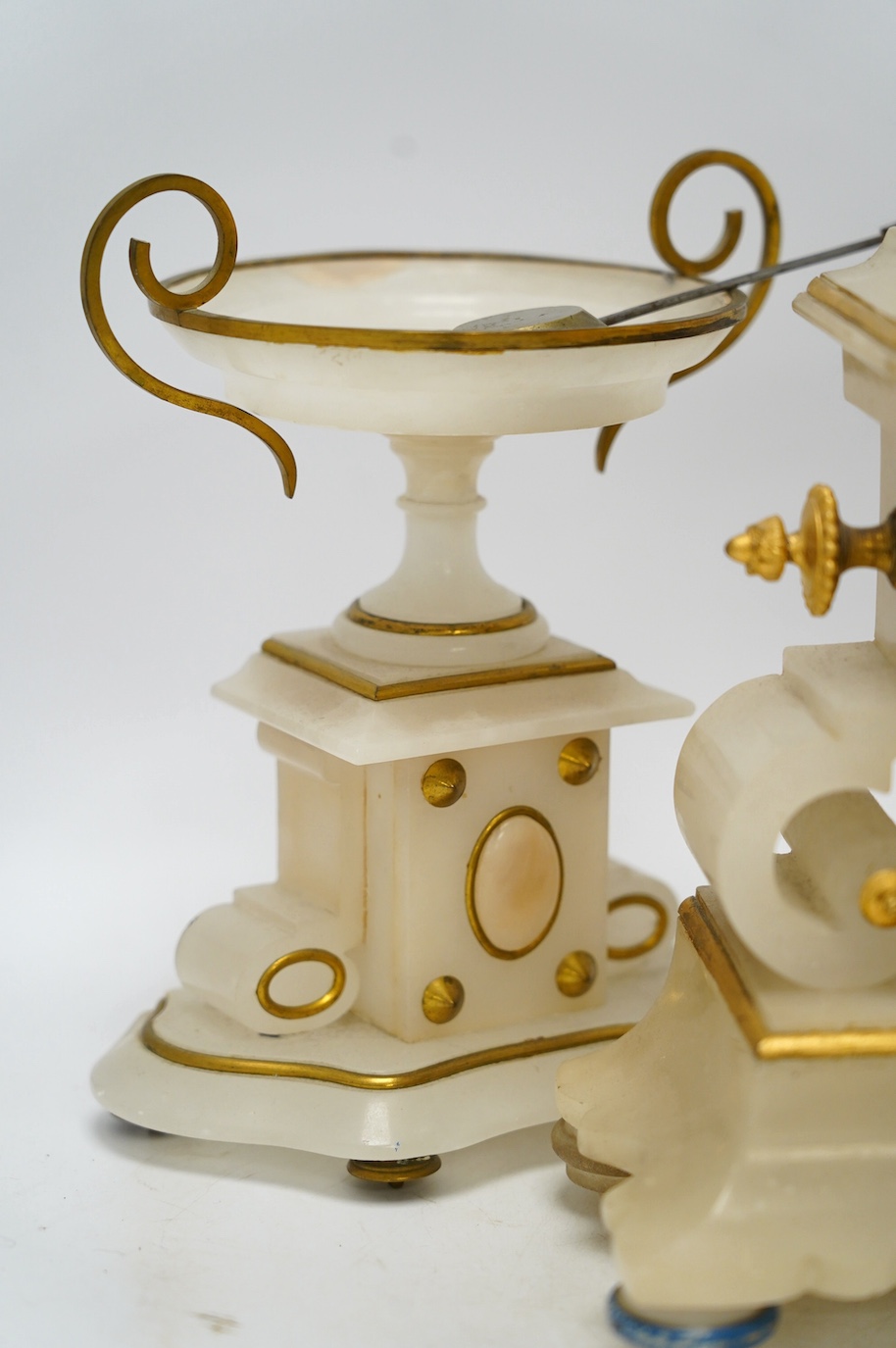 An early 20th century alabaster and gilt metal clock garniture with enamel panels, surmounted with a lion, with pendulum, no key, clock 30cm high. Condition - poor